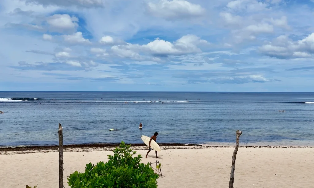 Playa tranquila con surfistas y nubes, imprescindible en Siargao